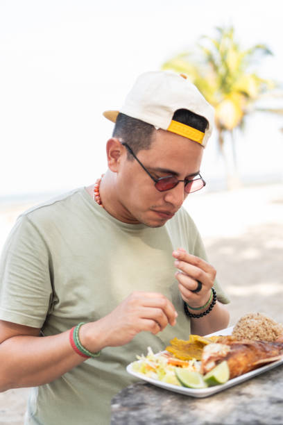 istock Latin Man relishing a traditional meal outdoors with the ocean backdrop 1967664214