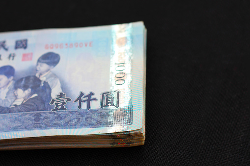 Enlarged view on a portion of a 1000 Taiwan dollar bill showing Chinese characters and four school children who are looking at a globe