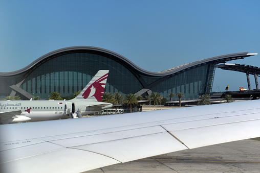Qatar Airways airplane from Qatar outside the terminal on the ground on a sunny afternoon in Doha, Qatar