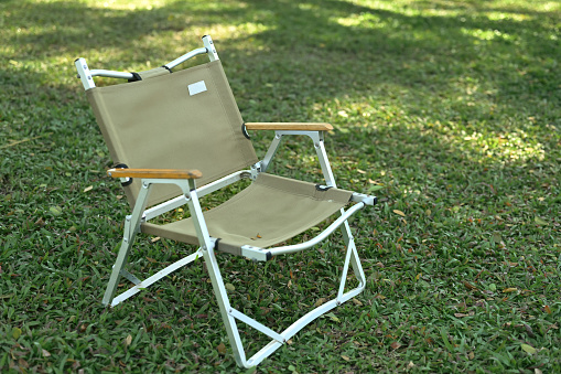 A green lawn chair setting on the grass field, No body.