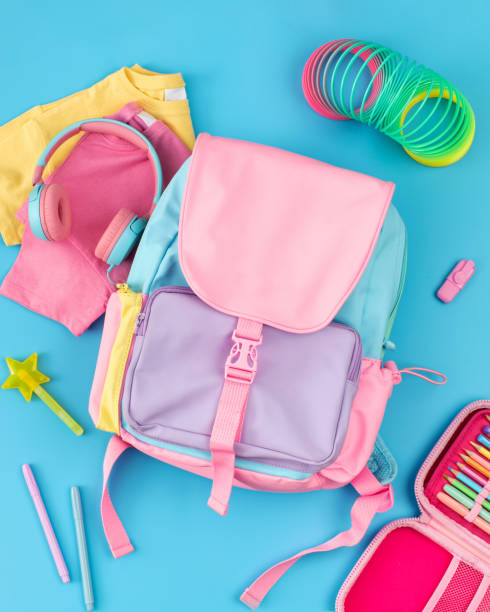 istock A children's colored backpack on a blue background, surrounded by toys and stationery. Elementary school 1967683239