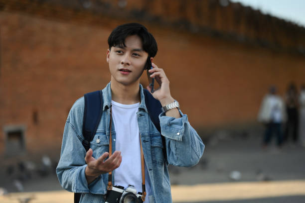 A backpacked male traveler talking on his mobile phone Tha Phae gate, at Chiangmai on background with copy space