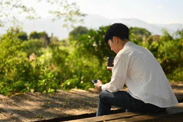 istock A Lonely Man Using Smartphone When Sitting on the Bench with Outdoors beautiful natural view 1967687003