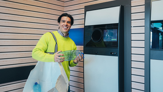 Man recycling plastic bottle via reverse vending machine