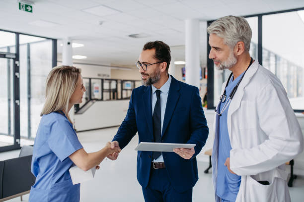 istock Pharmaceutical sales representative talking with doctors in medical building, presenting new product on tablet. 1967709976
