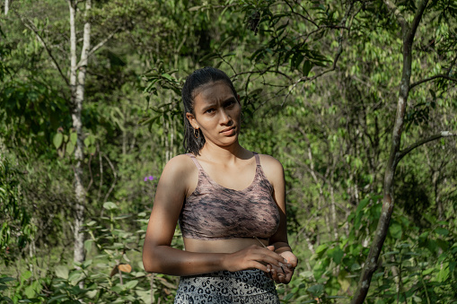 young woman outdoors in the middle of nature wearing sportswear while pouting