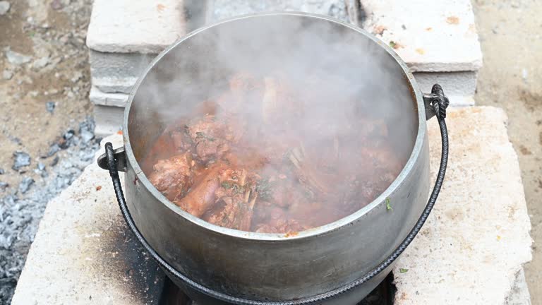 Firewood meal preparing kid Peruvian Andean dish. Food on the fire. Cast iron pot cooking fire wood in stone oven background.