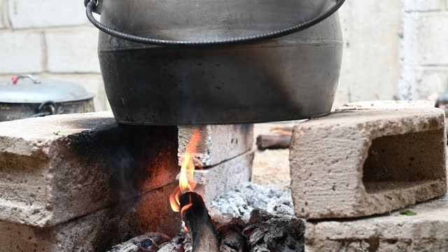 Holiday food fire cooking pot firewood. Preparing food on fire. Cast iron pot fire wood burning in stone oven cooking background.