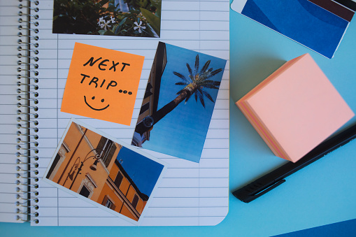 Using sticky notes to make handmade travel  photo album or scrapbook. Memories, good vibes, adventures, good life. Directly above view.