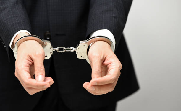 Hands of a man in a suit being handcuffed