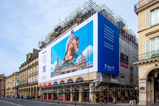 Paris, France - January 27, 2024: Giant advertising billboard sponsored by Allianz about the Paris 2024 Olympic games (show jumping) on the scaffoldings of the restoration work of a parisian building