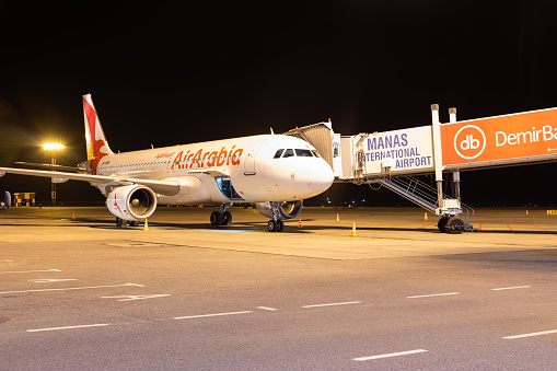 Bishkek, Kyrgyzstan - September 26, 2023: A6-ANR Air Arabia Airbus A320-214(WL) with jetway at the Manas International Airport at night