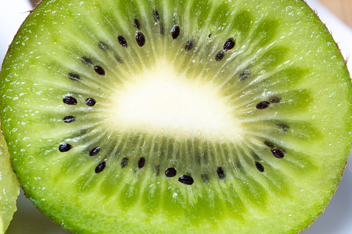 Green and yellow kiwi fruits on a plate top view