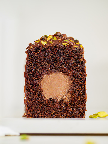 Travel Cake or Tube Cake or Voyage Cake filled center tube ganache and topped chocolate icing and pistachio. Chocolate loaf cake with chocolate cream-cheese filled center. Copy space. Vertical