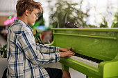 Teenage boy playing on a green piano in a café