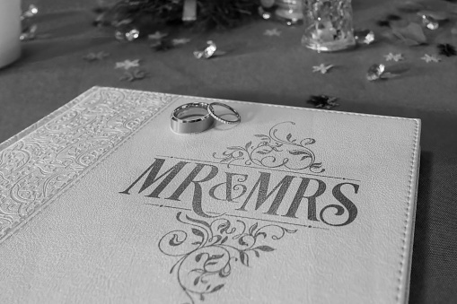 A close-up of wedding rings on a beautifully embossed 'Mr & Mrs' guestbook.
