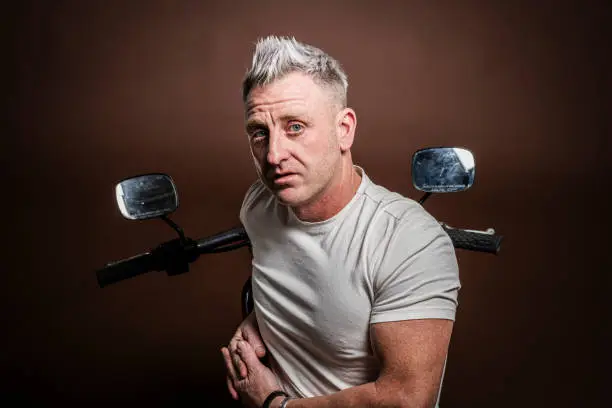 Middle-aged man posing next to his motorcycle