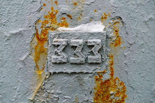 Number 333 made of grey metal elements with traces of rust