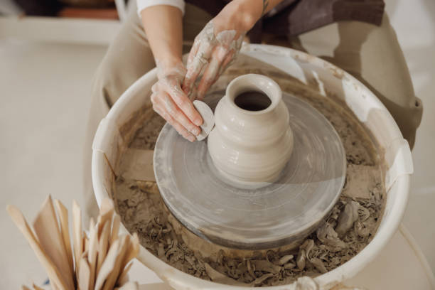 istock Female potter in apron making shape of clay vase on spinning pottery tool in ceramic workshop 1967936719
