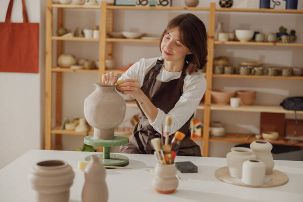 istock Smiling young female ceramist wearing apron work with unfired clay vase in pottery studio 1967938418
