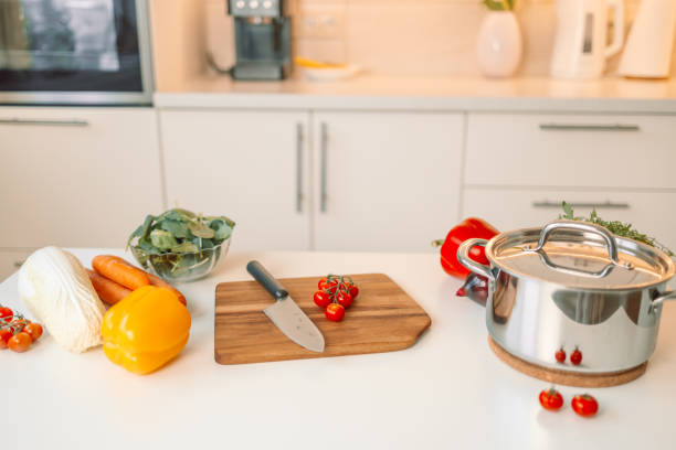 istock Different fresh vegetables on white table in modern kitchen. Products and blurred view of kitchen interior on background 1967947608