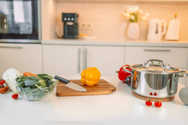 istock Different fresh vegetables on white table in modern kitchen. Products and blurred view of kitchen interior on background 1967949136