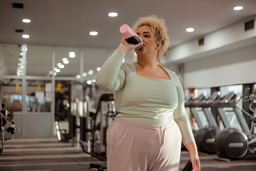 Plus Size Woman Drinking Water in the Gym After Exhausting Training, Weight Loss Workout