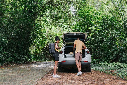 Hiking couple taking backpacks from the trunk of the car