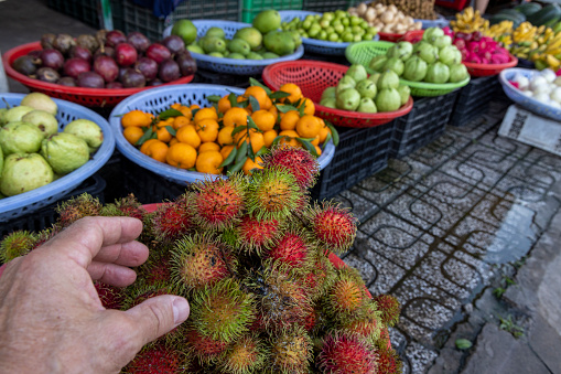 POV of hand reaching for tropical fruit in outdoor market
