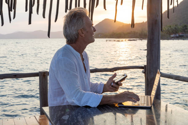 istock Mature man works on laptop on pier 1967985265