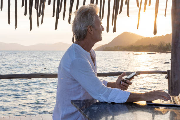 istock Mature man works on laptop on pier 1967986970