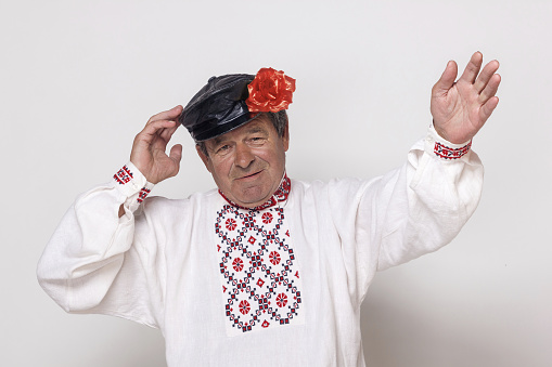 Mature man in a national Slavic shirt and cap with a red flower