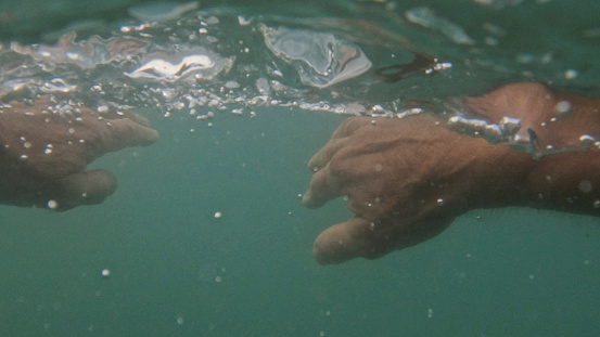 POV of hands swimming in sea water