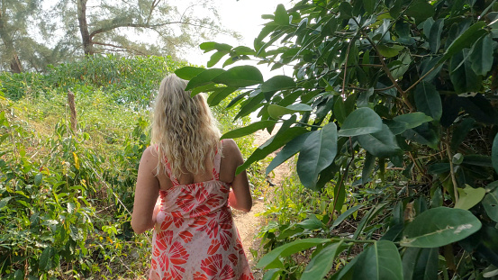 Rear view of mature woman walking through jungle