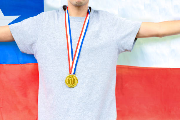 Triumphant Chilean male athlete proudly showcases a gold medal, symbolizing victory. Holding the Chilean flag, he embodies national pride during sporting events