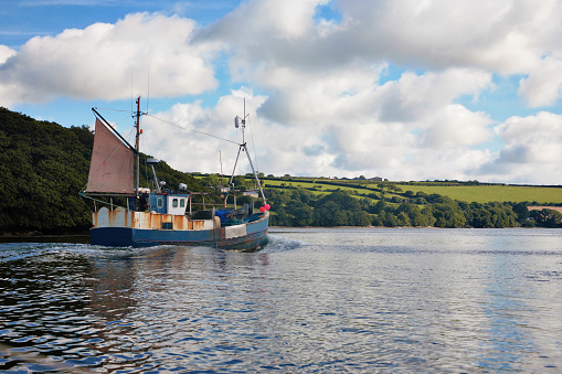Trawler heading out to sea in the estuary of the Helford River, Cornwall,  UK