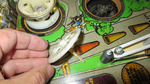 A vibrant carnival game features a tall bell tower adorned with bright lights and star badges. A mallet rests nearby, inviting players to test their strength.