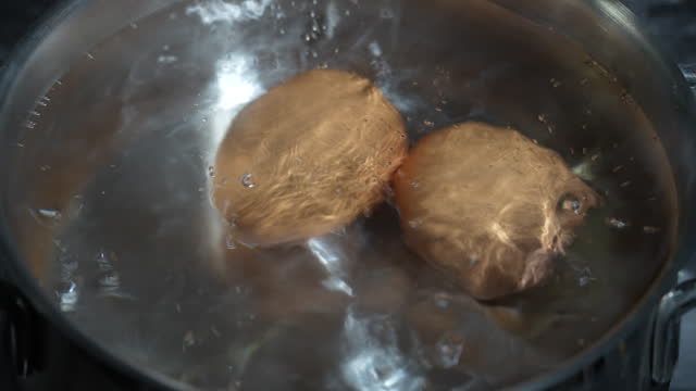 Saucepan with two chicken eggs in boiling water on a gas stove, closeup
