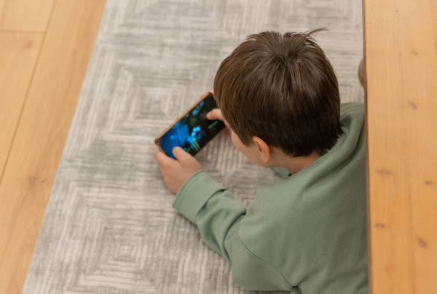 istock Little boy lying on the floor and playing with smart phone 1968029464