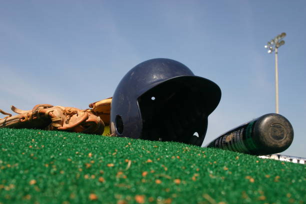 Baseball and softball equipment and gear on a green pitchers mound with blue sky
