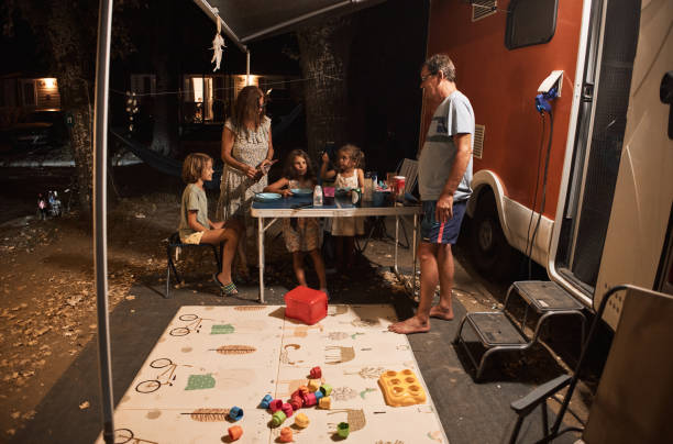 happy family talking at picnic table by the camper trailer in nature - motor home mobile home camping senior adult photos et images de collection