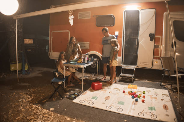 happy family talking at picnic table by the camper trailer in nature - motor home mobile home camping senior adult photos et images de collection