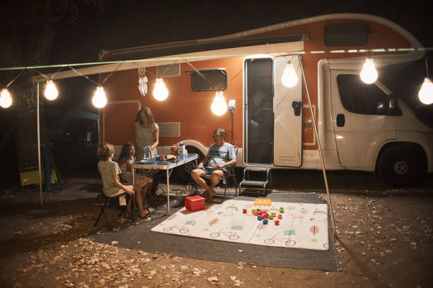 happy family talking at picnic table by the camper trailer in nature - motor home mobile home camping senior adult photos et images de collection