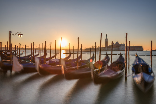 Long exposure of Venice, Italy with anchored gondolas on the Grand Canal at sunrise.