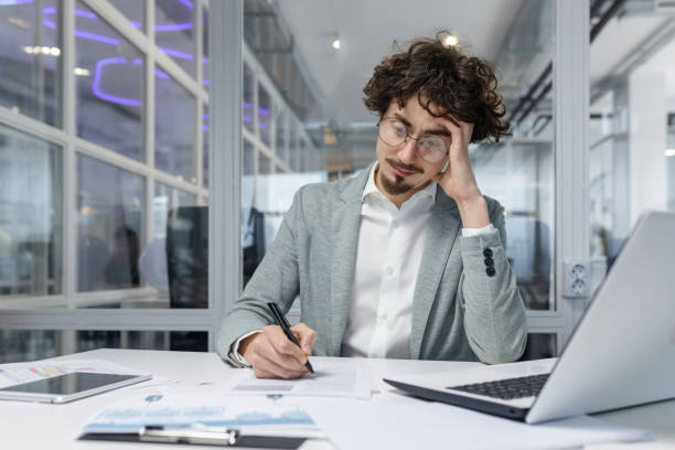 istock Serious and focused financier accountant on paper work inside office, mature man using calculator and laptop for calculating reports and summarizing accounts, businessman at work in casual clothes 1968099232