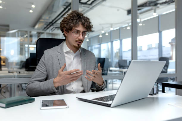 istock Dedicated young businessman engaged in work at modern office desk 1968100812