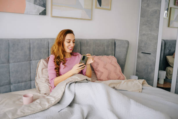 istock Woman lying on bed and using a phone 1968101898