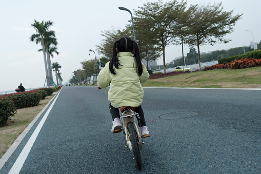 Back view of little girl riding bicycle