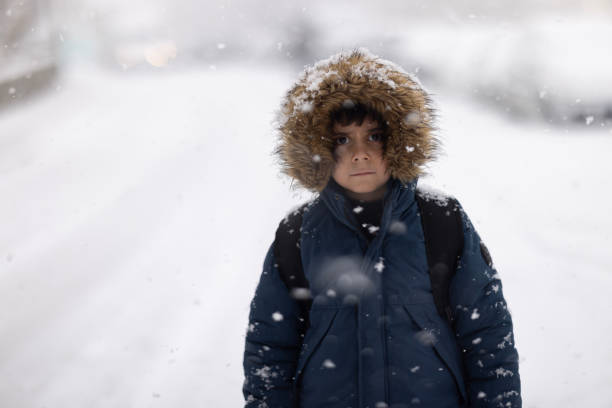 Happy kid boy with having fun with snow on way to school