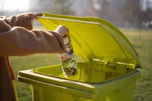 istock Woman with disability in hand throwing a plastic bottle into green trash bin 1968114101